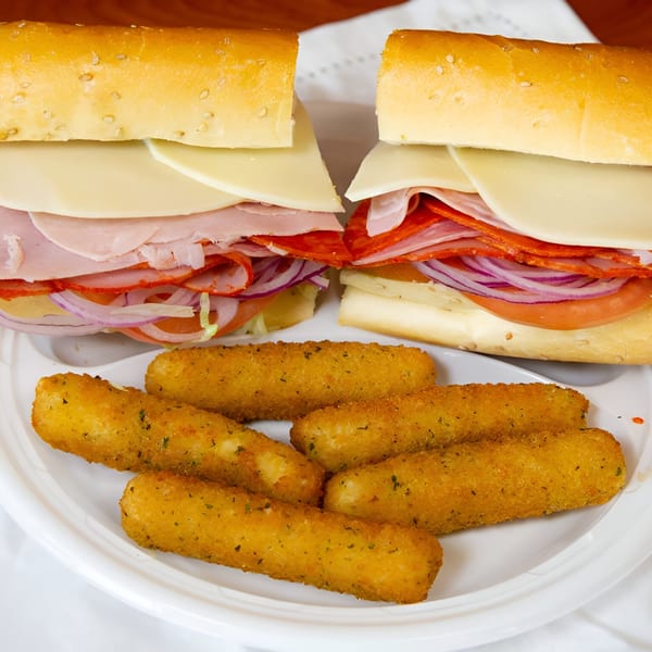 Two deli subs with cheese, meat, and vegetables, alongside a plate of mozzarella sticks.