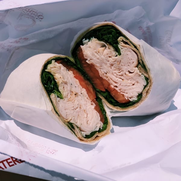 A Finn's Deli turkey wrap, cut in half, revealing sliced turkey, tomatoes, and lettuce.