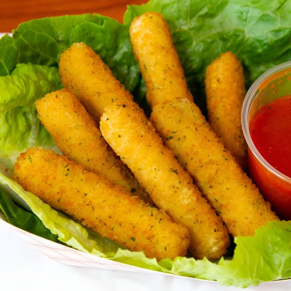 Golden-brown mozzarella sticks with herbs, served on lettuce with a side of red dipping sauce.