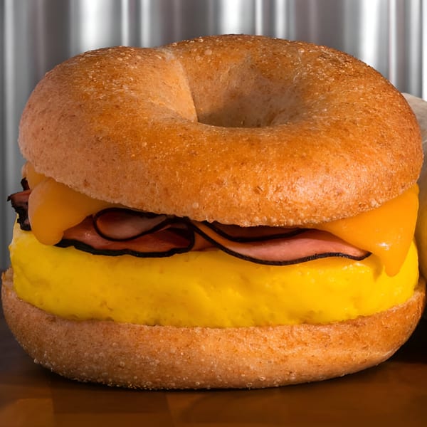 Finn's Deli breakfast bagel with egg, ham, and melted cheese, against a metallic background.