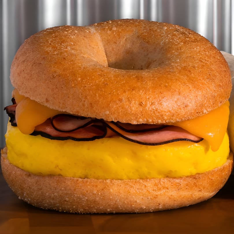 Finn's Deli breakfast bagel with egg, ham, and melted cheese, against a metallic background.